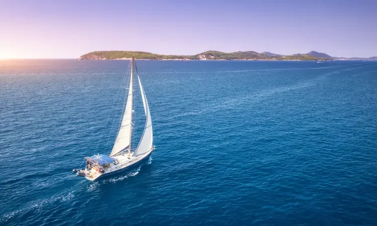 Adriatic sea in Croatia. Landscape with yacht, mountains, transparent blue water, sky at sunset