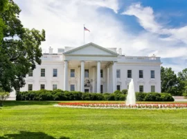 The White House on a summer day with the American flying over it.