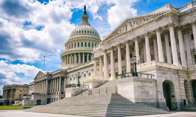 Bright mid-day view of the traditional neoclassical architecture of the Capitol Building’s dome, columns, and steps in Washington DC, USA