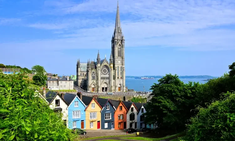 Colorful row houses with towering cathedral in background in the port town of Cobh, County Cork, Ireland