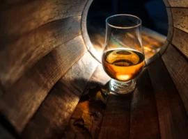 A glass of whiskey in oak barrels