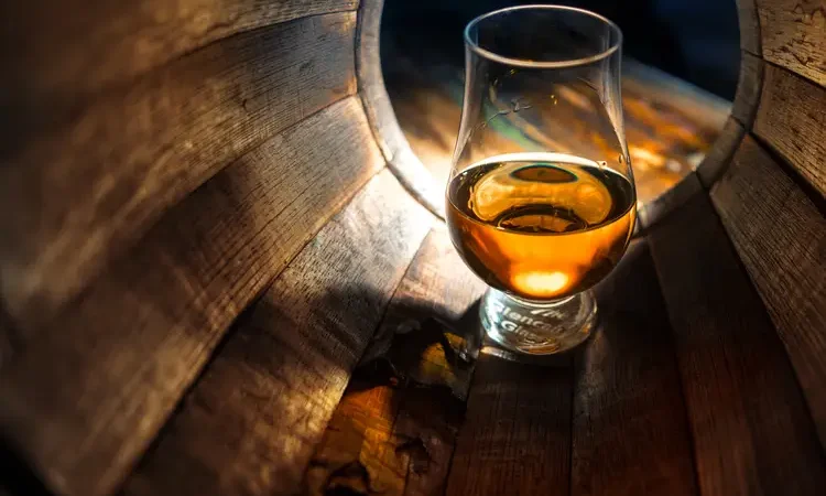 A glass of whiskey in oak barrels